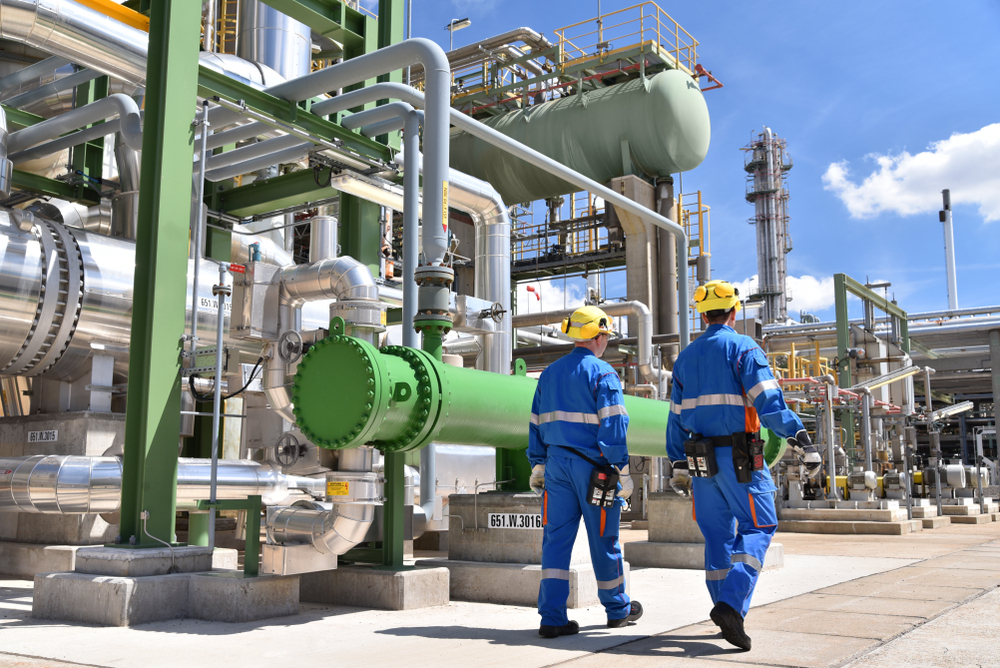 chemical industry plant - workers in work clothes in a refinery with pipes and machinery